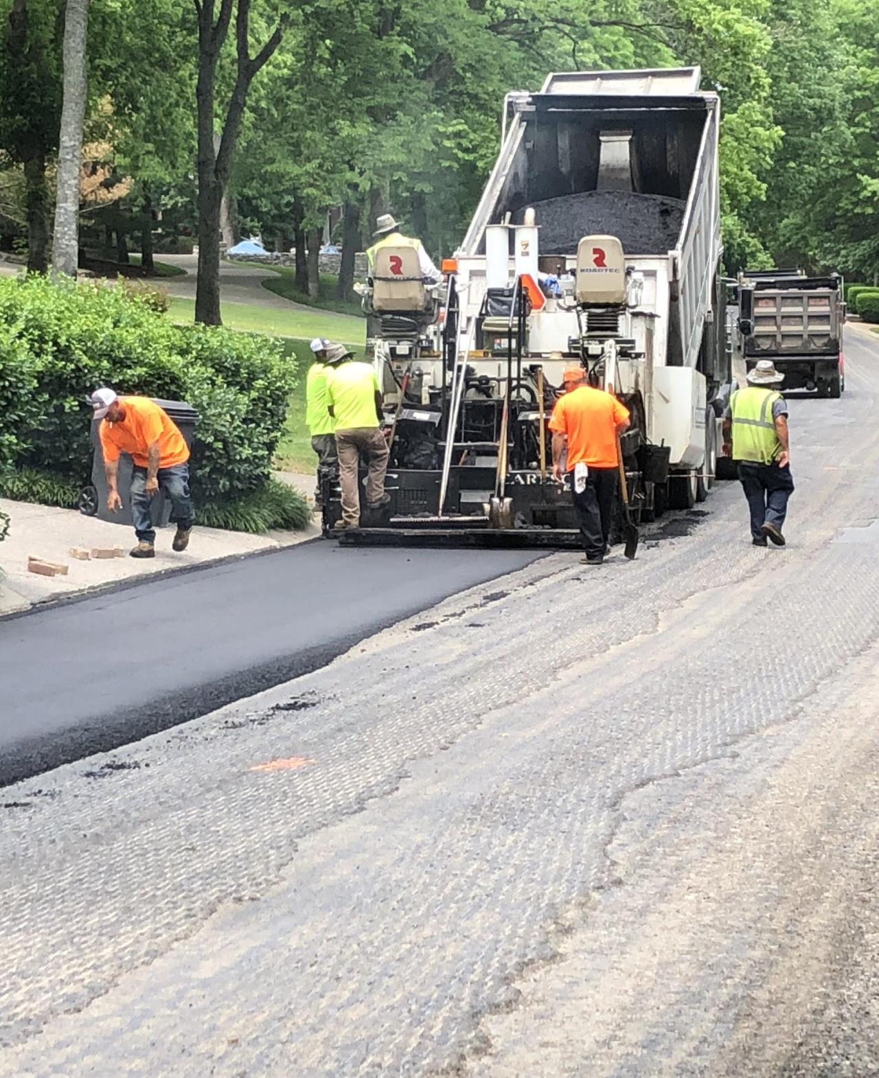 five men working on paving equipment